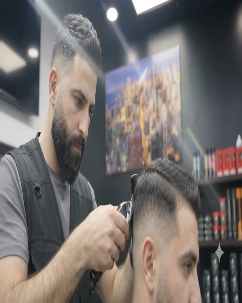 Barber shaping a client's fade under the shop lights